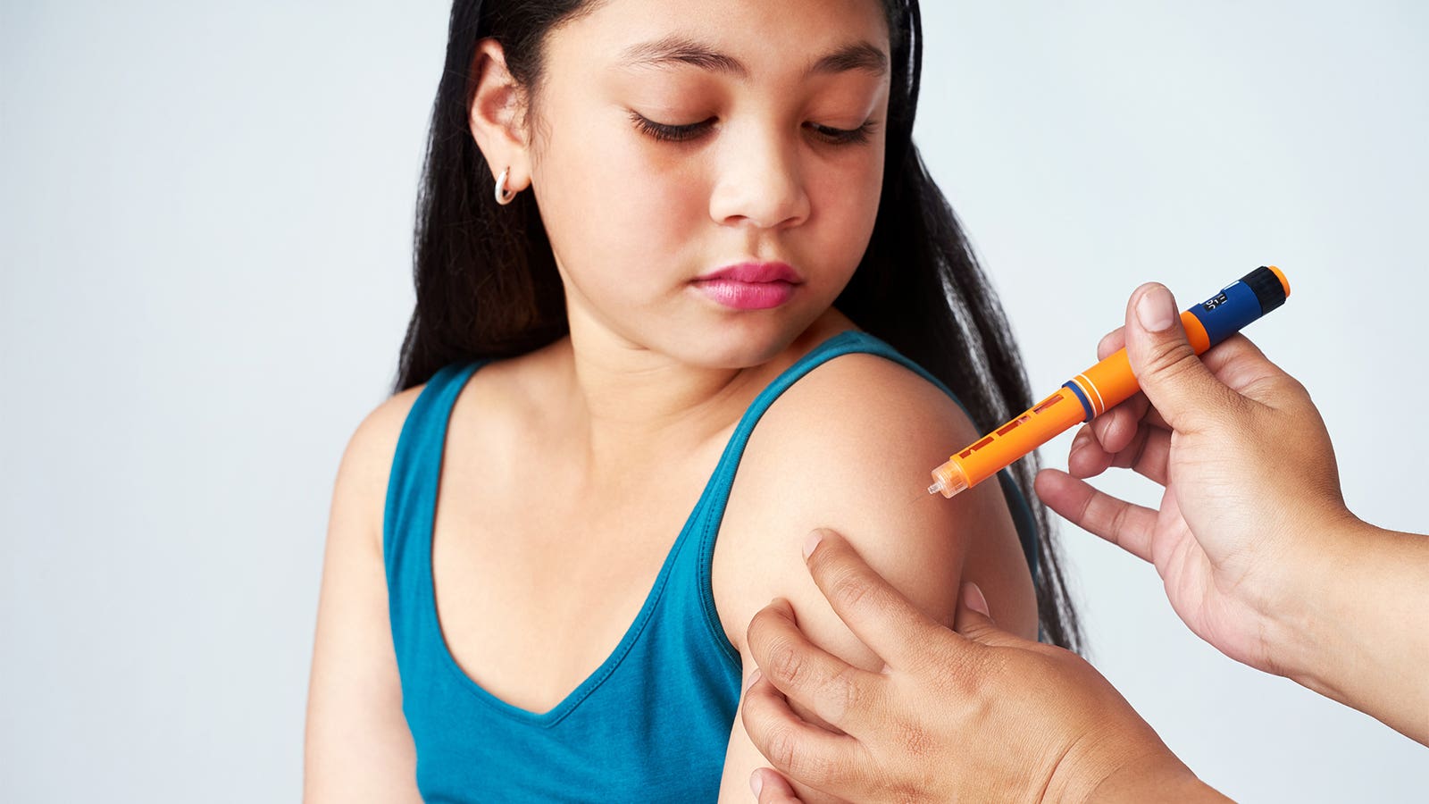 A young girl gets an insulin shot from her mother.