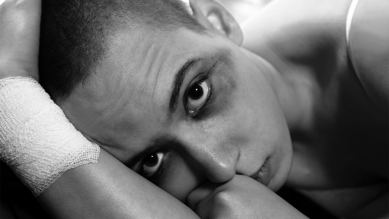 A close up portrait of a young teen laying down with a bandaged wrist.