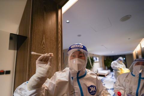 Une personne, portant des équipements de protection, tient un kit de test PCR dans un hôtel alors que les Jeux olympiques d'hiver de Pékin 2022, en février 2022.