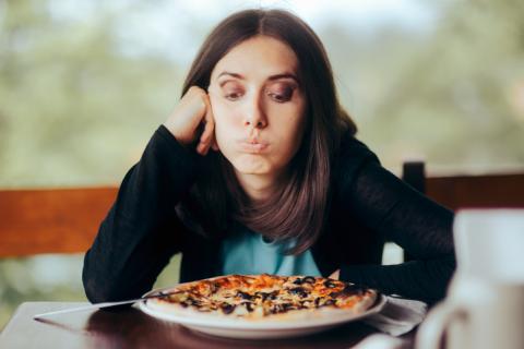 une femme déprimée regarde avec défi sa pizza.