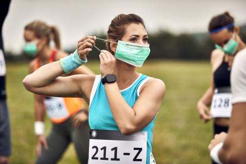 Une femme s'apprête à commencer un marathon, et enfile un masque.