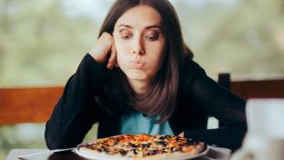 une femme déprimée regarde avec défi sa pizza.