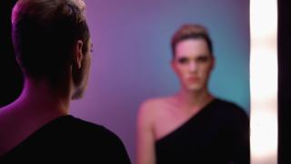 une personne transgenre se regarde dans le miroir.