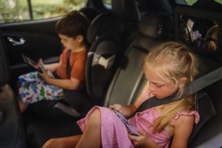 Des enfants jouent sur une tablette dans une voiture.