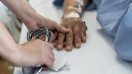 Soignant tenant la main d'un patient en fin de vie.