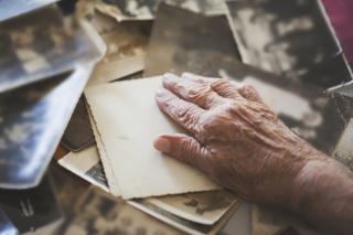 Une personne âgée a la main sur de vieilles photos.