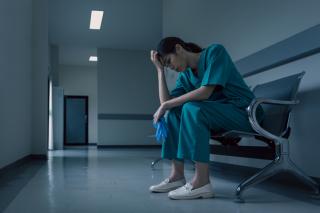 Une médecin fatiguée reprend son souffle dans le corridor d'un hôpital.
